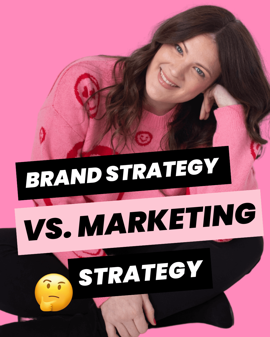 Brand strategist, Emily Lauren Dick, sitting and leaning on her hand, smiling and wearing a pink sweater with red happy faces.