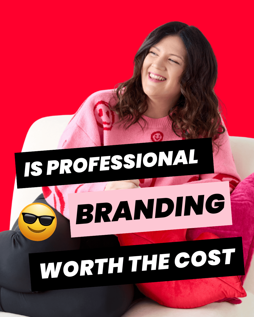 Brand strategist designer, Emily sitting on a white chair with red lip shaped pillow, wearing pink sweater, smiling and holding an iPad.